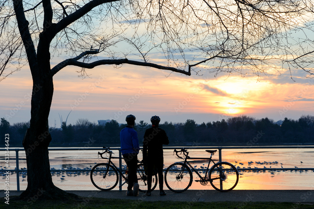 Obraz premium two bikers enjoy sunset in tidal basin with a view of Jefferson memorial during the winter season - Washington DC united states