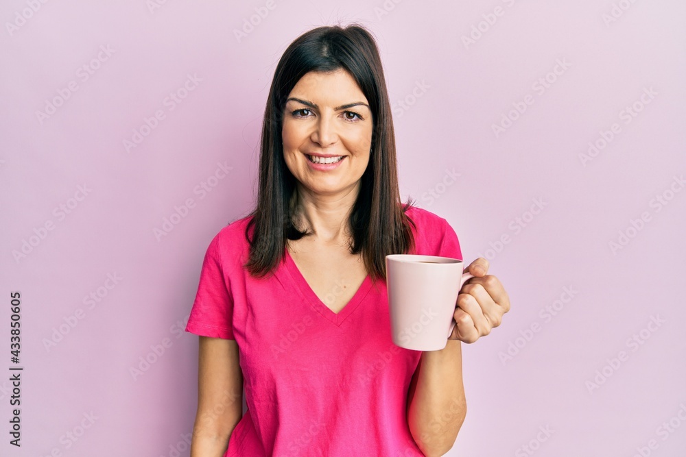Young hispanic woman drinking a cup of coffee covering mouth with hand, shocked and afraid for mistake. surprised expression Young hispanic woman drinking a cup of coffee covering mouth with hand, shocked and afraid for mistake. surprised expression