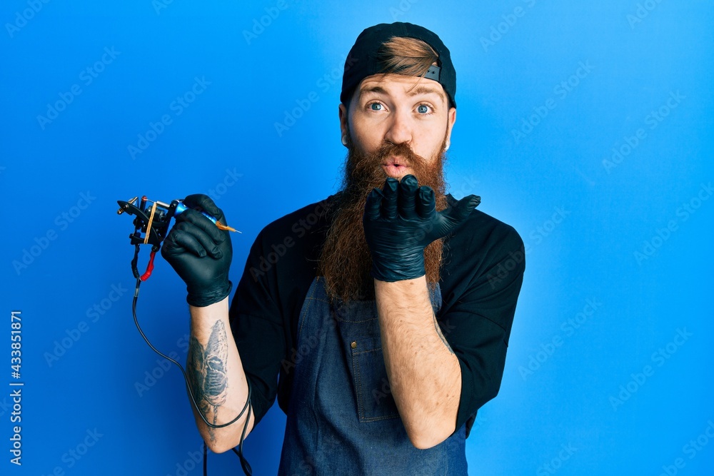 Redhead man with long beard tattoo artist wearing professional uniform and  gloves looking at the camera blowing a kiss with hand on air being lovely  and sexy. love expression. Stock Photo |