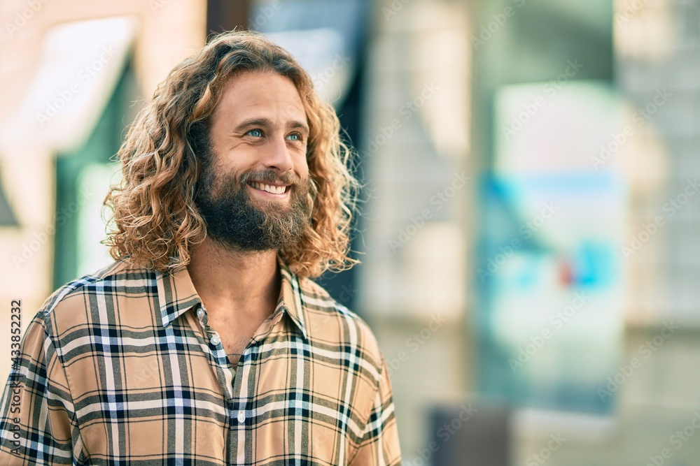 Obraz premium Young caucasian man with long hair smiling happy at the city.