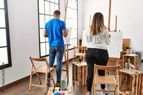 Two students on back view painting at art school.