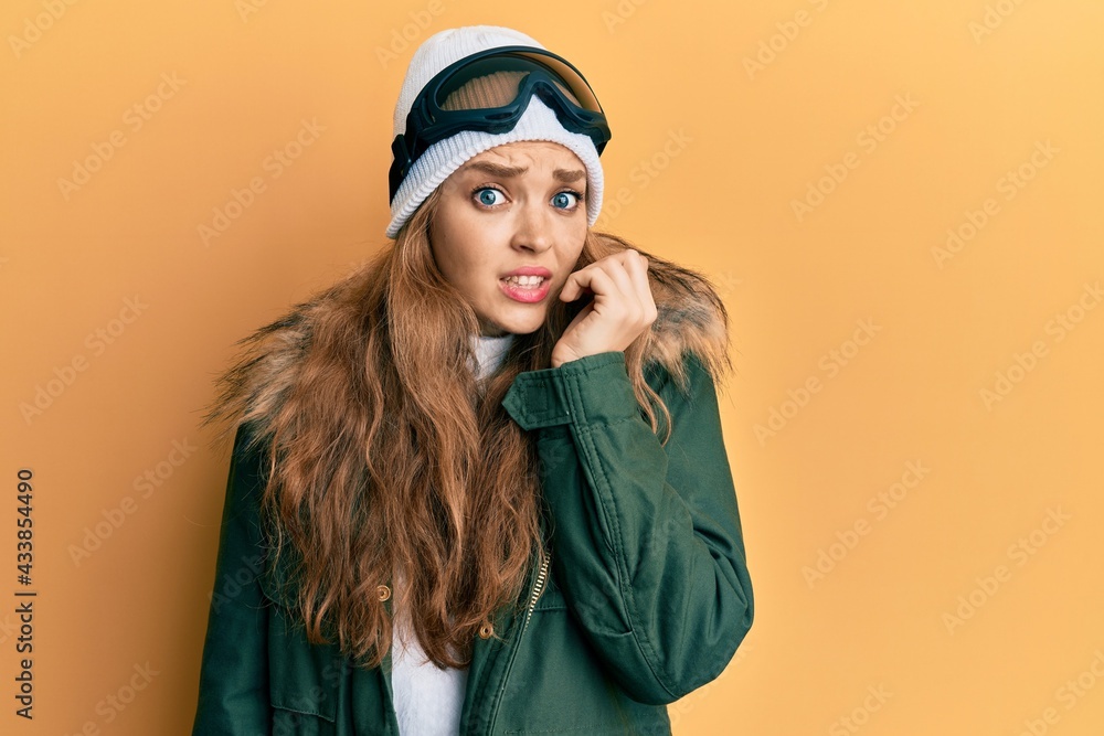 Beautiful blonde caucasian woman wearing snow wear and sky glasses looking stressed and nervous with hands on mouth biting nails. anxiety problem. Beautiful blonde caucasian woman wearing snow wear and sky glasses looking stressed and nervous with hands on mouth biting nails. anxiety problem.