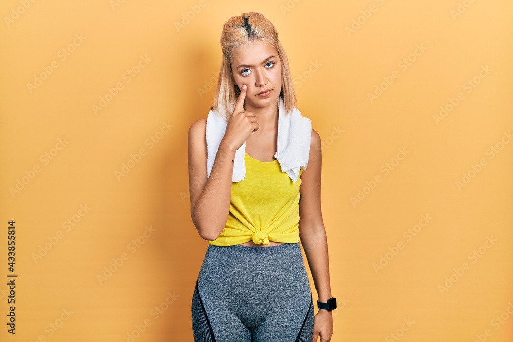 Beautiful blonde sports woman wearing workout outfit pointing to the eye watching you gesture, suspicious expression