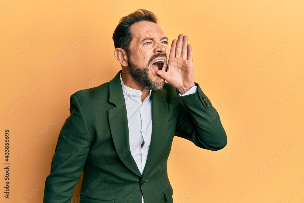 Middle age man wearing business suit shouting and screaming loud to side with hand on mouth. communication concept. Middle age man wearing business suit shouting and screaming loud to side with hand on mouth. communication concept.