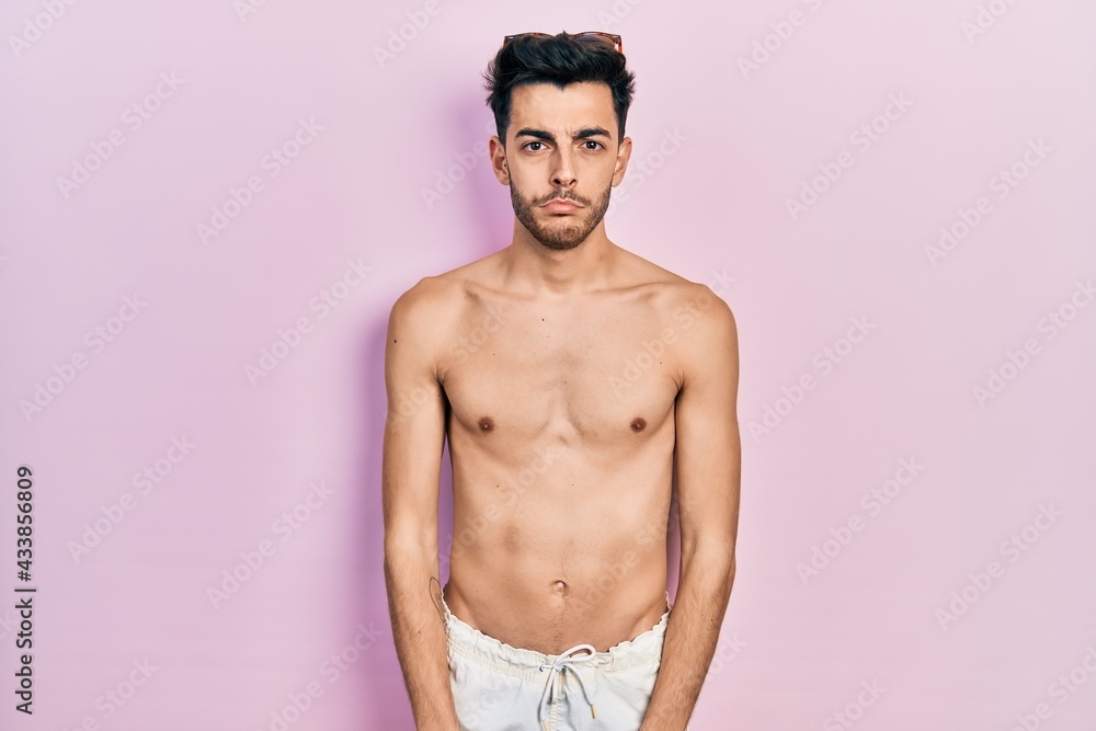 Young hispanic man wearing swimwear shirtless depressed and worry for distress, crying angry and afraid. sad expression. Young hispanic man wearing swimwear shirtless depressed and worry for distress, crying angry and afraid. sad expression.