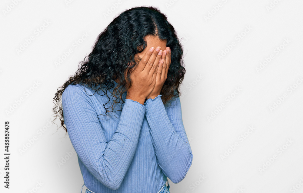 Young hispanic woman with curly hair wearing casual clothes with sad expression covering face with hands while crying. depression concept. Young hispanic woman with curly hair wearing casual clothes with sad expression covering face with hands while crying. depression concept.
