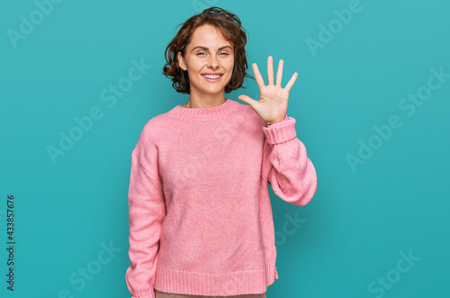 Young hispanic woman wearing casual clothes showing and pointing up with fingers number five while smiling confident and happy.
