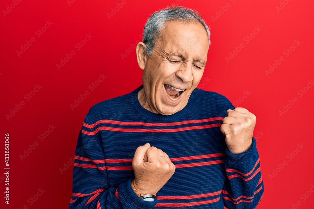 Senior hispanic man wearing casual clothes celebrating surprised and amazed for success with arms raised and eyes closed Senior hispanic man wearing casual clothes celebrating surprised and amazed for success with arms raised and eyes closed