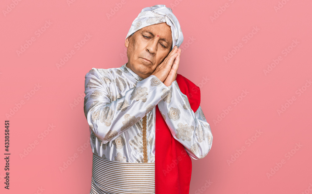 Senior hispanic man wearing tradition sherwani saree clothes sleeping tired dreaming and posing with hands together while smiling with closed eyes. Senior hispanic man wearing tradition sherwani saree clothes sleeping tired dreaming and posing with hands together while smiling with closed eyes.