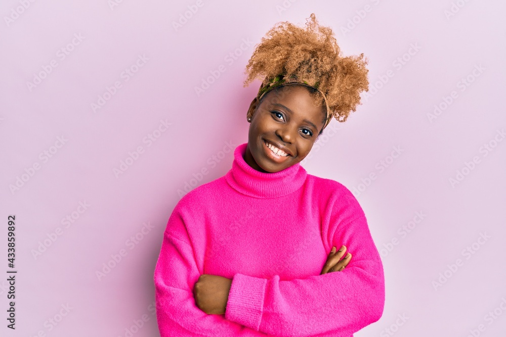 Fototapeta premium Young african woman with afro hair wearing casual winter sweater happy face smiling with crossed arms looking at the camera. positive person.
