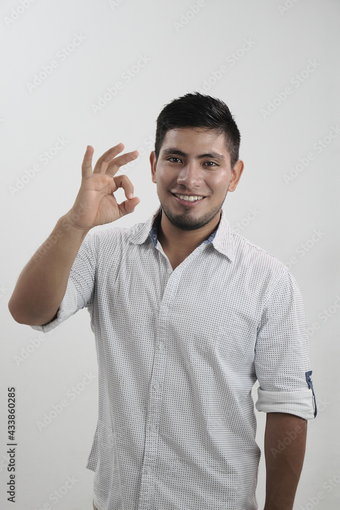 Hombre latino sonriendo haciendo gesto de aprobación okey Hombre latino sonriendo haciendo gesto de aprobación okey