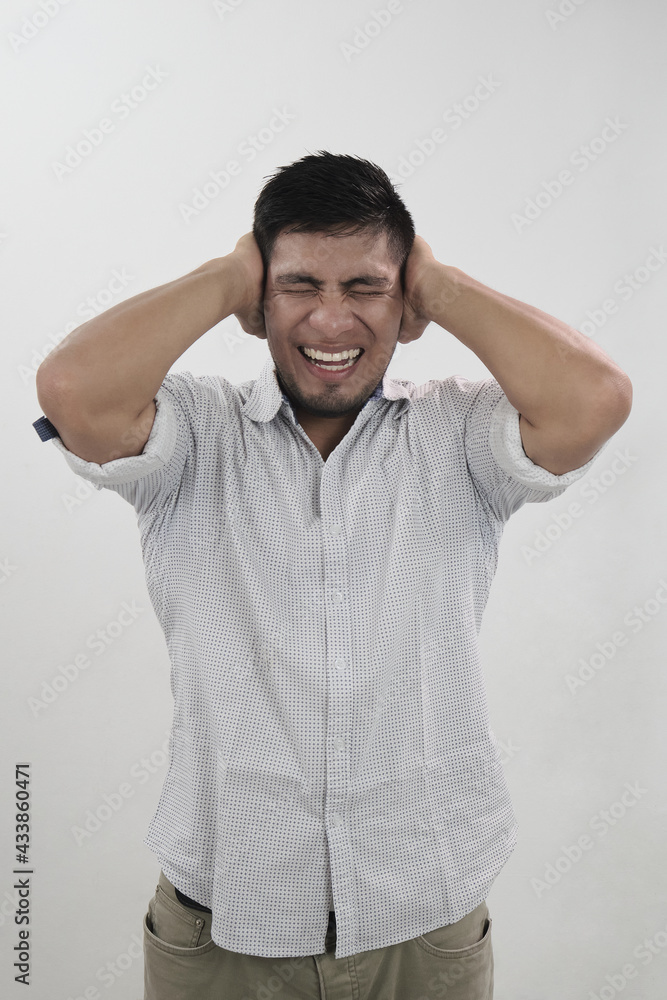 hombre latino tapa sus oídos con gesto de dolor en su rostro hombre latino tapa sus oídos con gesto de dolor en su rostro