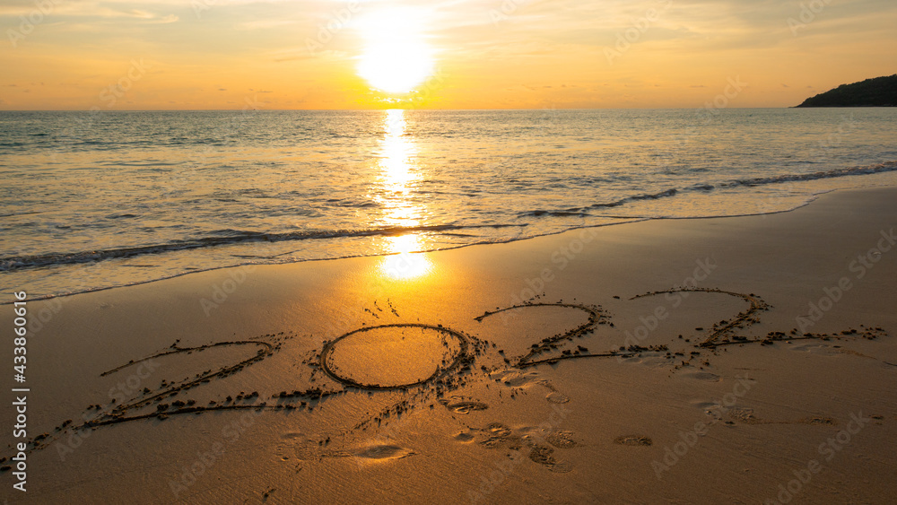 Obraz premium Happy New Year 2022, Lettering on the beach with waves and sunset sky Numbers 2022 year on the seashore, Message hand written in the golden sand on beautiful sunset or sunrise golden sky background