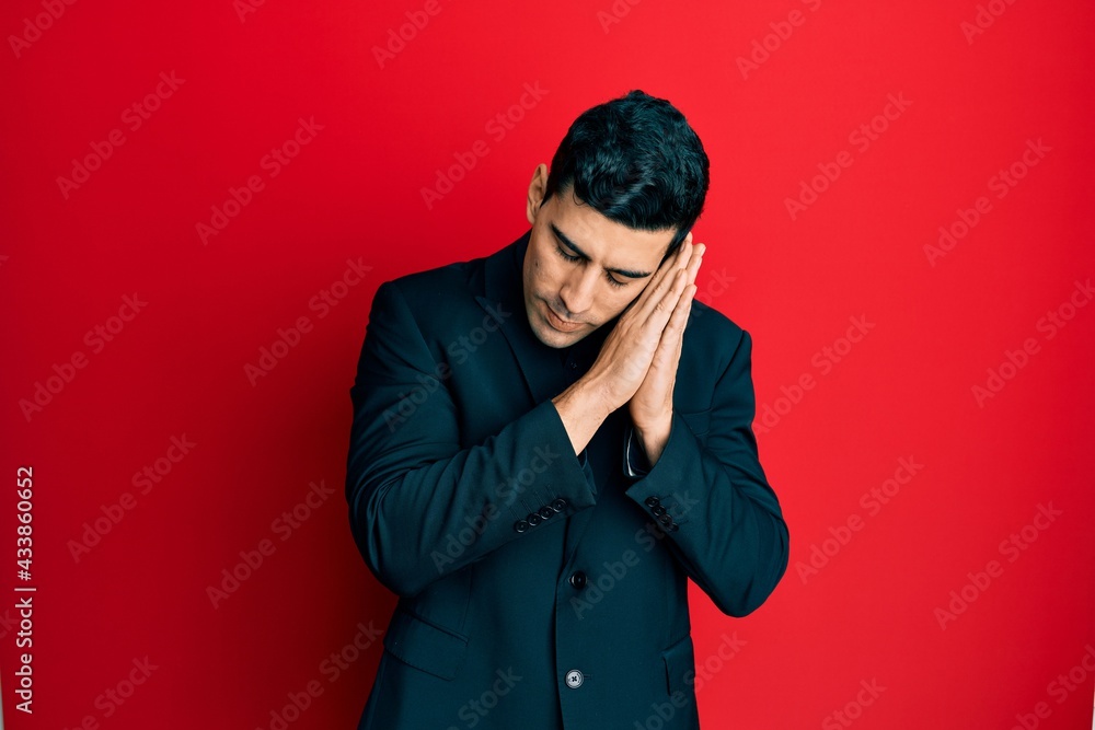 Handsome hispanic man wearing business clothes sleeping tired dreaming and posing with hands together while smiling with closed eyes. Handsome hispanic man wearing business clothes sleeping tired dreaming and posing with hands together while smiling with closed eyes.