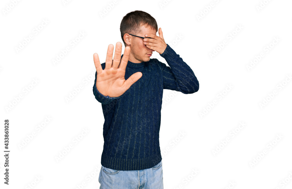 Young blond man wearing casual clothes and glasses covering eyes with hands and doing stop gesture with sad and fear expression. embarrassed and negative concept. Young blond man wearing casual clothes and glasses covering eyes with hands and doing stop gesture with sad and fear expression. embarrassed and negative concept.