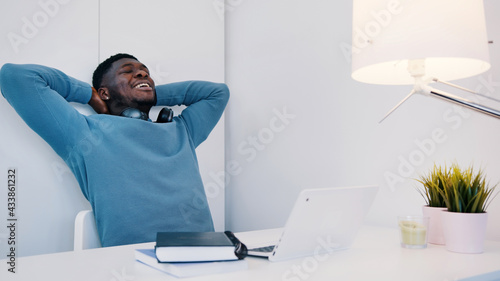 Man wearing headphones sitting at the table. A laptop is placed in front of him. Man in a good mood and smiling looking at the laptop screen. Concept of video calling or online classes. . High quality
