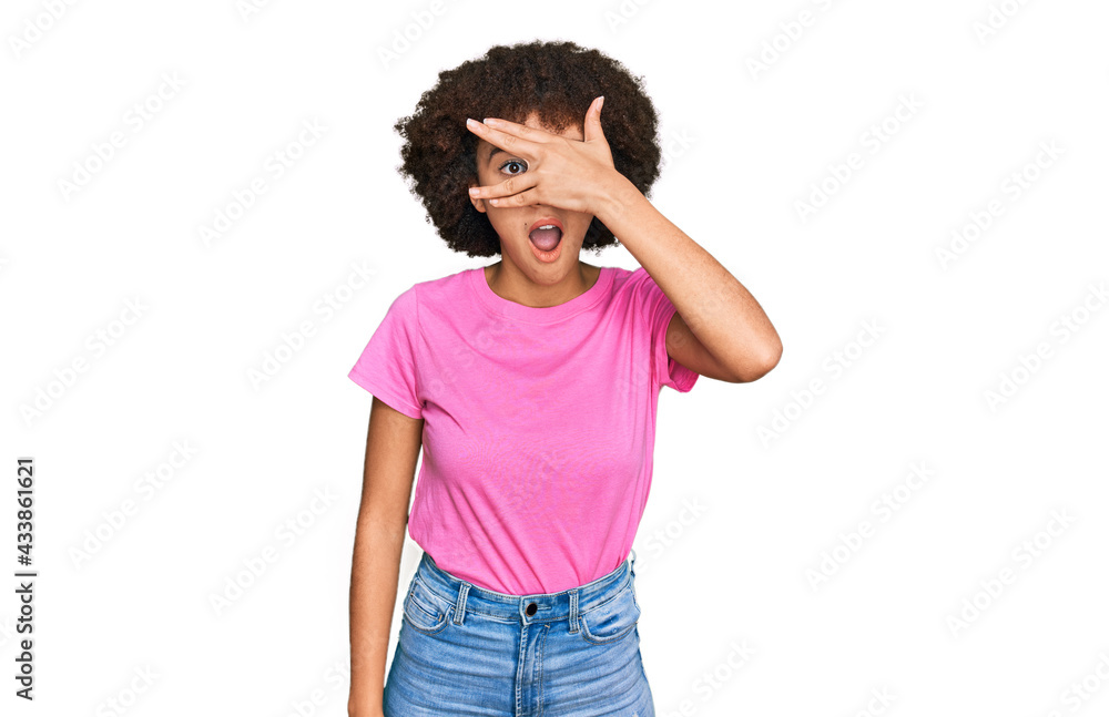 Young hispanic girl wearing casual clothes peeking in shock covering face and eyes with hand, looking through fingers with embarrassed expression. Young hispanic girl wearing casual clothes peeking in shock covering face and eyes with hand, looking through fingers with embarrassed expression.