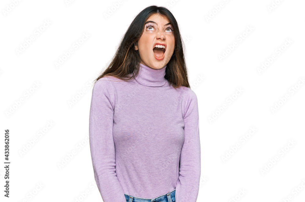 Young beautiful teen girl wearing turtleneck sweater angry and mad screaming frustrated and furious, shouting with anger. rage and aggressive concept. Young beautiful teen girl wearing turtleneck sweater angry and mad screaming frustrated and furious, shouting with anger. rage and aggressive concept.