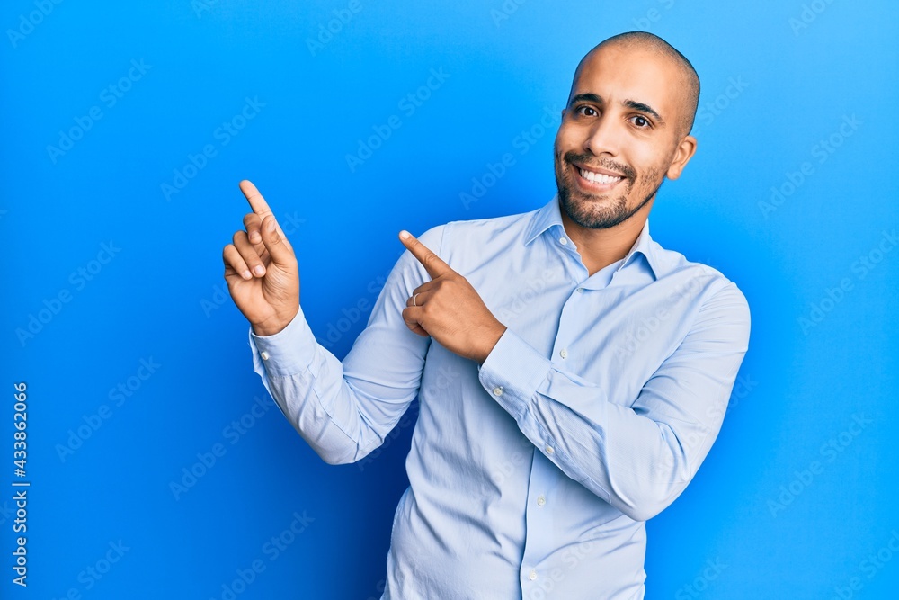 Hispanic adult man wearing business shirt over blue background smiling and looking at the camera pointing with two hands and fingers to the side. Hispanic adult man wearing business shirt over blue background smiling and looking at the camera pointing with two hands and fingers to the side.
