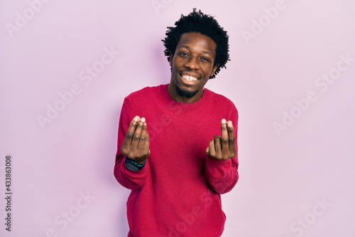 Young african american man wearing casual clothes doing money gesture with hands, asking for salary payment, millionaire business