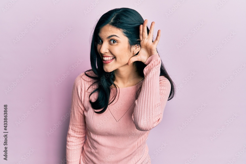 Young hispanic woman wearing casual clothes smiling with hand over ear listening and hearing to rumor or gossip. deafness concept. Young hispanic woman wearing casual clothes smiling with hand over ear listening and hearing to rumor or gossip. deafness concept.