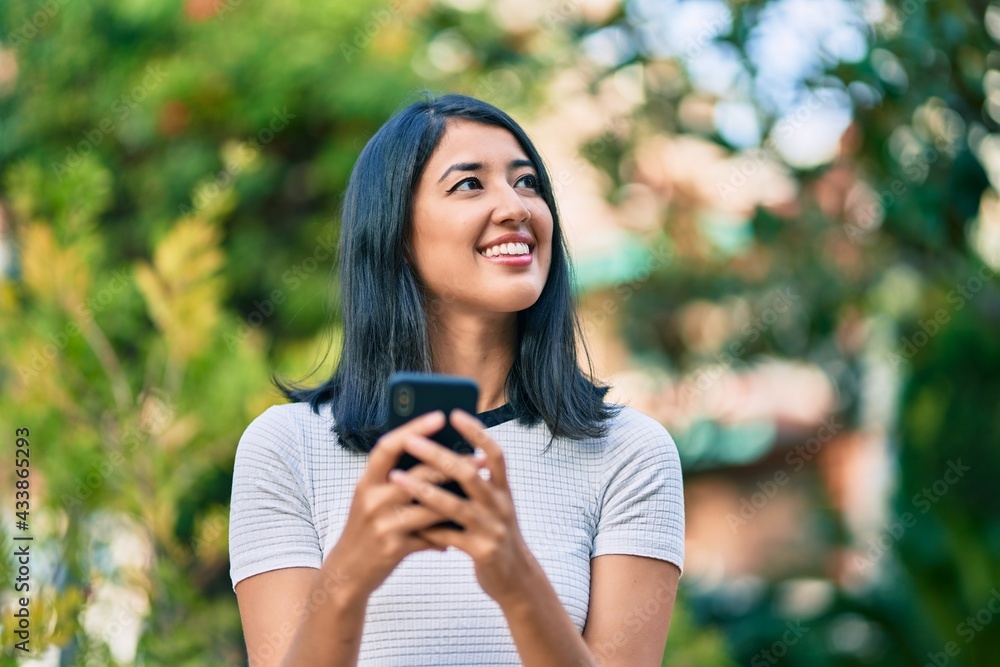 Young hispanic woman smiling happy using smartphone at the city. Young hispanic woman smiling happy using smartphone at the city.