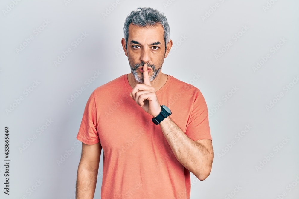 Handsome middle age man with grey hair wearing casual t shirt asking to be quiet with finger on lips. silence and secret concept. Handsome middle age man with grey hair wearing casual t shirt asking to be quiet with finger on lips. silence and secret concept.