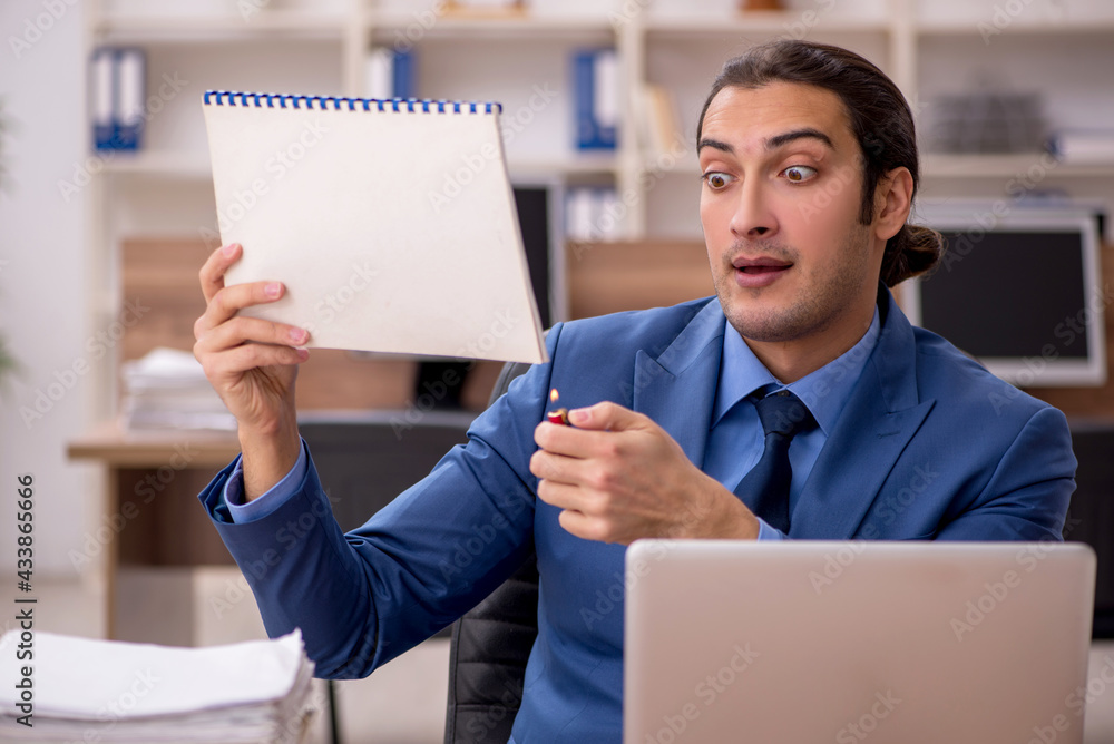Young male employee burning paper at workplace Young male employee burning paper at workplace