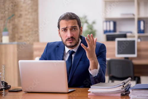 Young businessman employee unhappy with excessive work in the of