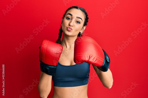 Young brunette girl using boxing gloves looking at the camera blowing a kiss being lovely and sexy. love expression. © Krakenimages.com