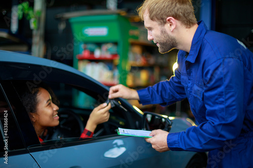 A female customer get car key from mechanic engineer.