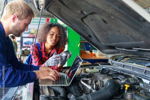 A Russian Male mechanic with tablet pc computer making system diagnostic in car at workshop. car service, repair, technology, maintenance and people concept