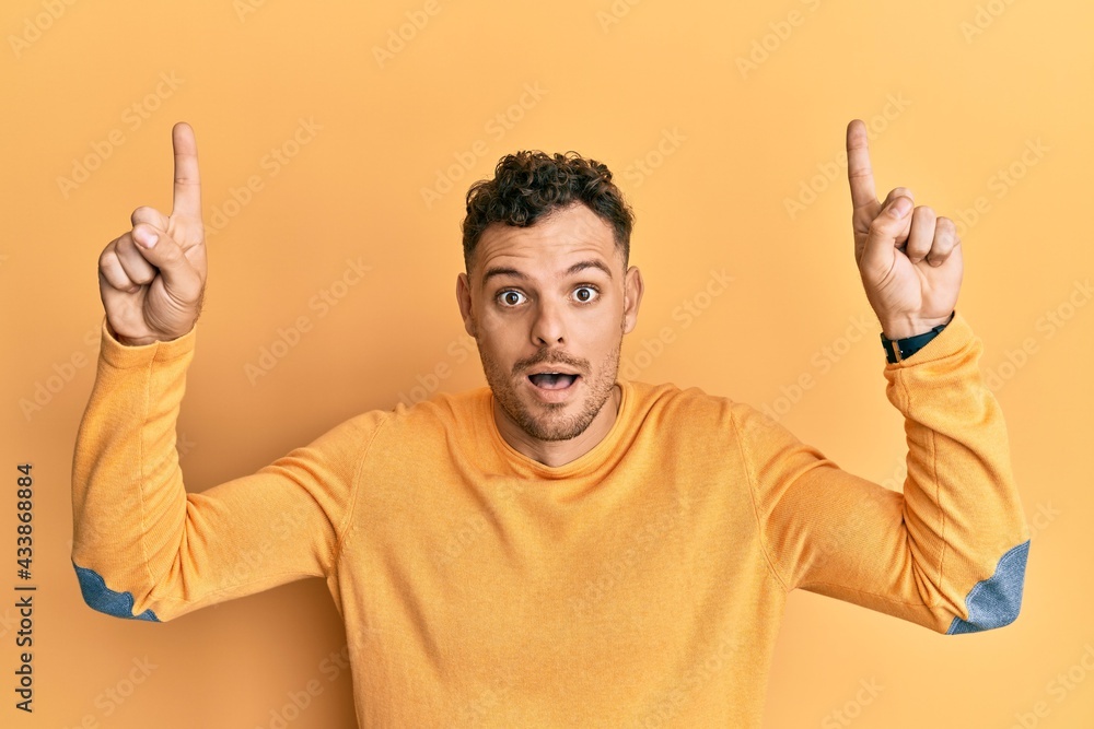 Young hispanic man pointing up with fingers afraid and shocked with surprise and amazed expression, fear and excited face. Young hispanic man pointing up with fingers afraid and shocked with surprise and amazed expression, fear and excited face.