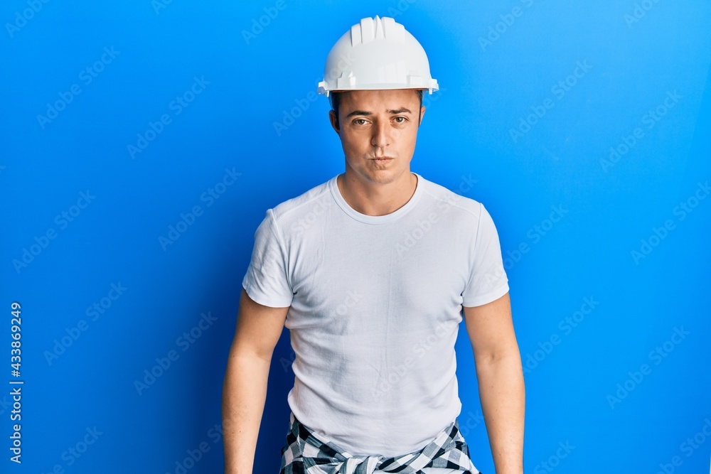 Handsome young man wearing builder uniform and hardhat depressed and worry for distress, crying angry and afraid. sad expression.