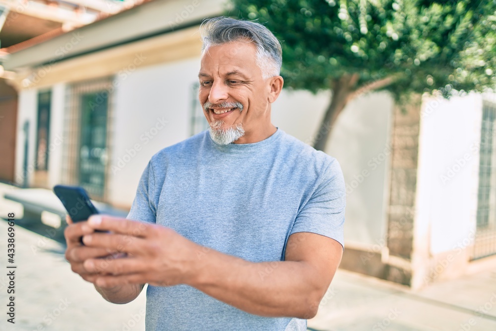 Middle age hispanic grey-haired man smiling happy using smartphone at the city. Middle age hispanic grey-haired man smiling happy using smartphone at the city.