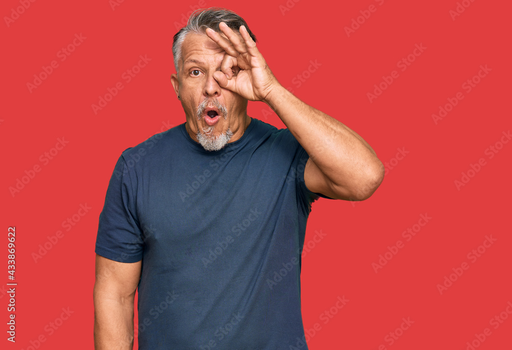 Middle age grey-haired man wearing casual clothes doing ok gesture shocked with surprised face, eye looking through fingers. unbelieving expression. Middle age grey-haired man wearing casual clothes doing ok gesture shocked with surprised face, eye looking through fingers. unbelieving expression.
