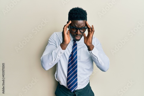 Handsome black man wearing glasses business shirt and tie with hand on head for pain in head because stress. suffering migraine.