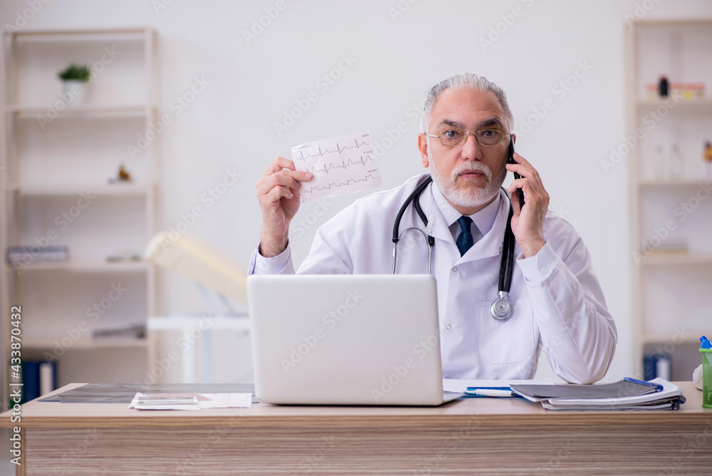 Old male doctor cardiologist working in the clinic Old male doctor cardiologist working in the clinic