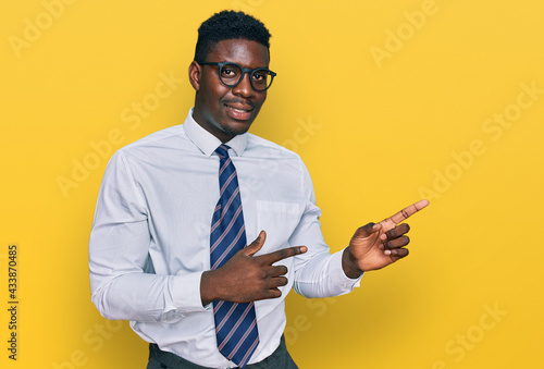 Handsome business black man wearing white shirt and tie smiling and looking at the camera pointing with two hands and fingers to the side.