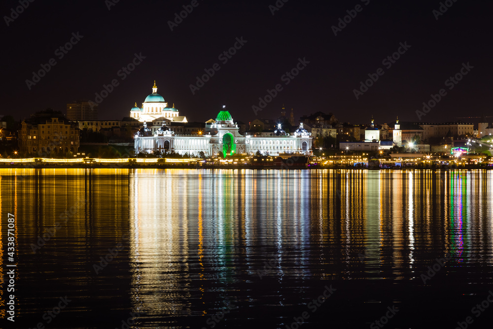 The beautifully illuminated embankment is reflected in the Kazanka River in the city of Kazan on a clear warm summer night