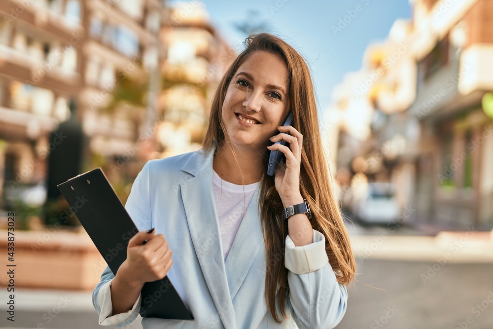 Young blonde businesswoman smiling happy talking on the smartphone at the city. Young blonde businesswoman smiling happy talking on the smartphone at the city.