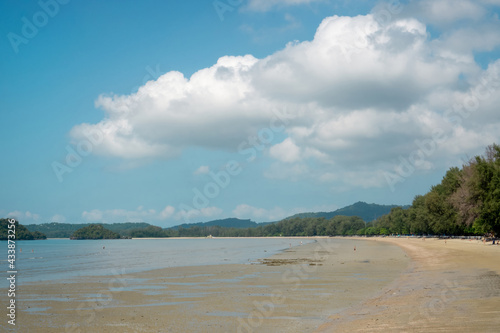 Landscape of sea sand beach under blue sky and white fluffy clouds, mountain on background
