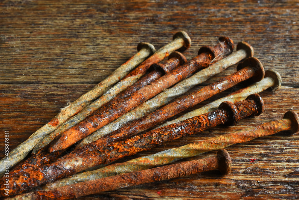 A close up image of several old and rusted carpentry nails on a dark wooden nails. A close up image of several old and rusted carpentry nails on a dark wooden nails.