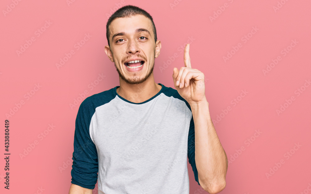 Hispanic young man wearing casual clothes pointing finger up with successful idea. exited and happy. number one. Hispanic young man wearing casual clothes pointing finger up with successful idea. exited and happy. number one.