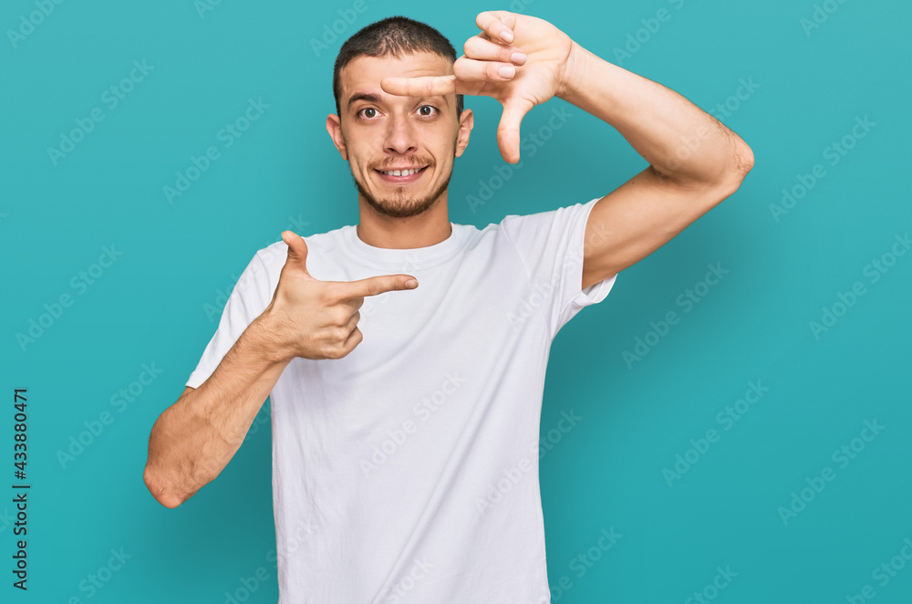 Fototapeta premium Hispanic young man wearing casual white t shirt smiling making frame with hands and fingers with happy face. creativity and photography concept.