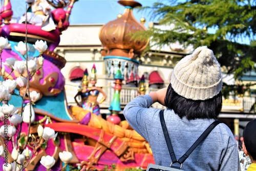 A little girl in a crochet hat watches a colorful float parade in a theme park