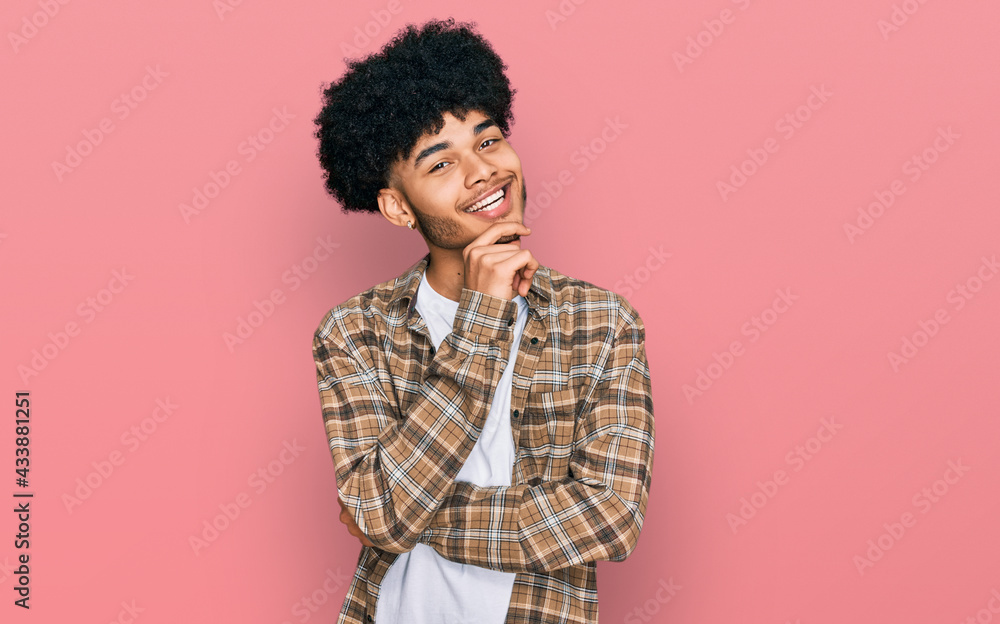 Young african american man with afro hair wearing casual clothes looking confident at the camera with smile with crossed arms and hand raised on chin. thinking positive. Young african american man with afro hair wearing casual clothes looking confident at the camera with smile with crossed arms and hand raised on chin. thinking positive.