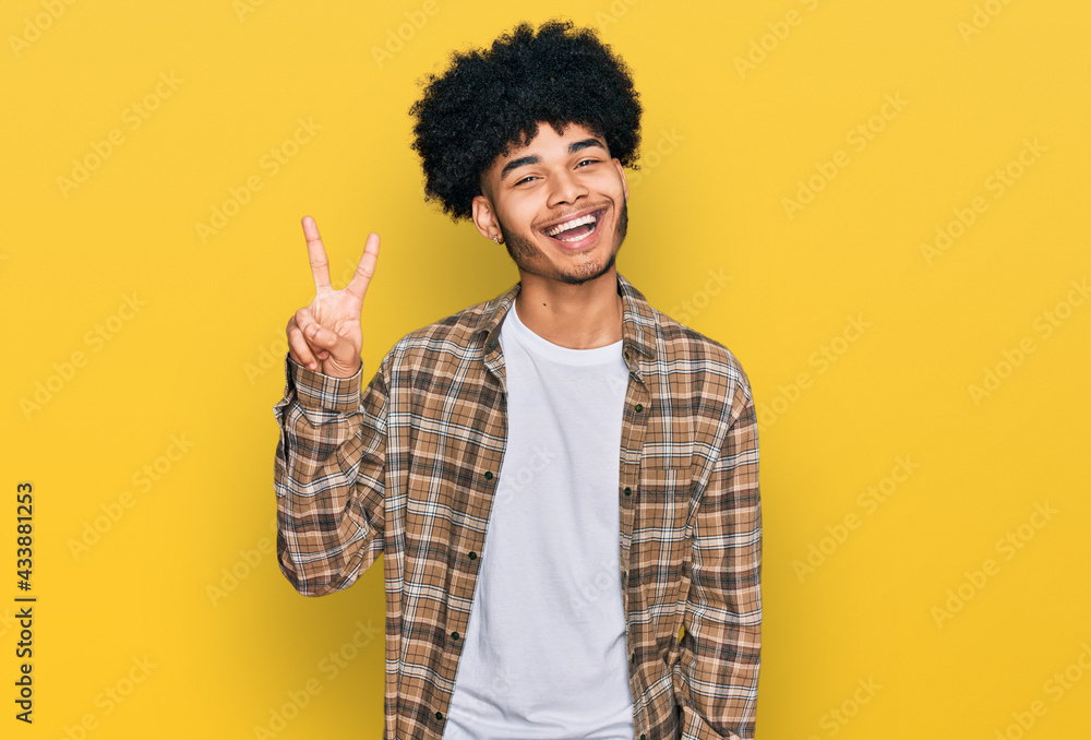 Young african american man with afro hair wearing casual clothes showing and pointing up with fingers number two while smiling confident and happy. Young african american man with afro hair wearing casual clothes showing and pointing up with fingers number two while smiling confident and happy.