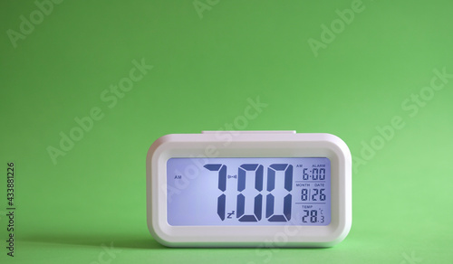 Digital alarm clock on table with green background. Copy space. photo