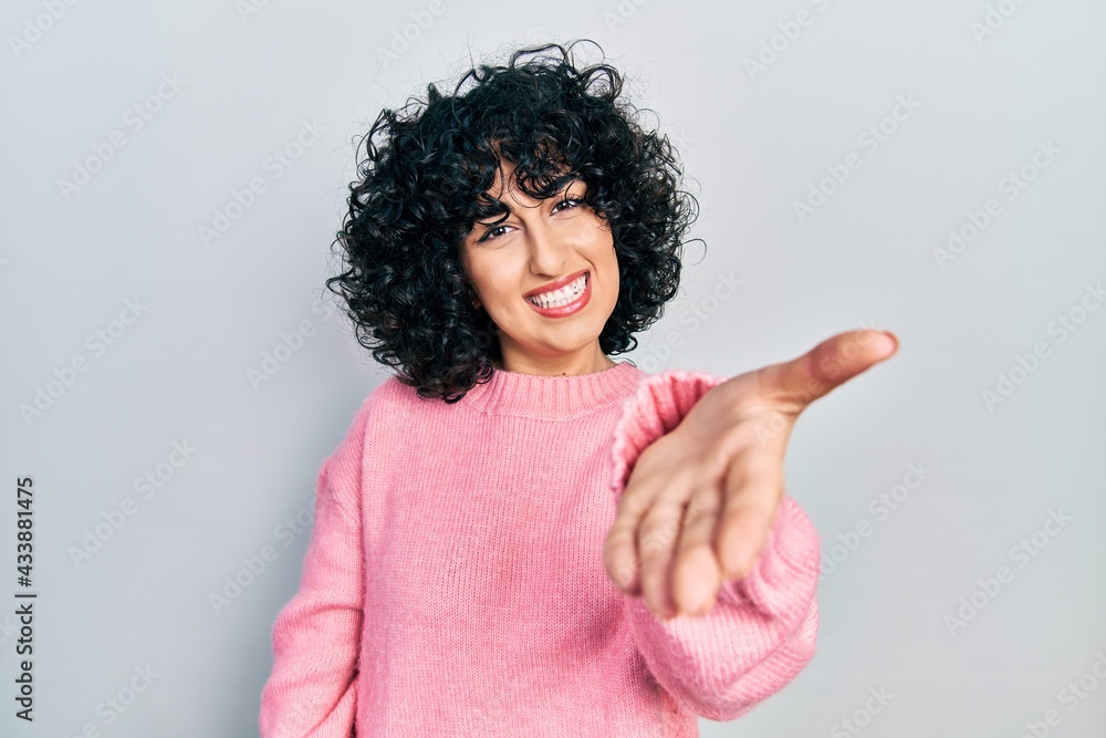 Young middle east woman wearing casual clothes smiling cheerful offering palm hand giving assistance and acceptance. Young middle east woman wearing casual clothes smiling cheerful offering palm hand giving assistance and acceptance.